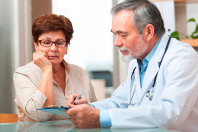 Doctor talking to his female senior patient at the office